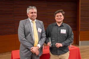 two people stand, one is holding a glass plaque