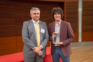 two people stand, one is holding a glass plaque