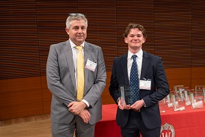 two people stand, one is holding a glass plaque