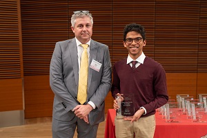two people stand, one is holding a glass plaque