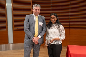two people stand, one is holding a glass plaque