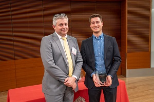 two people stand, one is holding a glass plaque