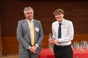 two people stand, one is holding a glass plaque