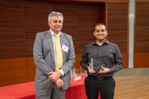 two people stand, one is holding a glass plaque