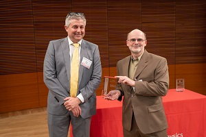 two people stand, one is holding a glass plaque
