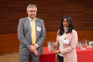 two people stand, one is holding a glass plaque