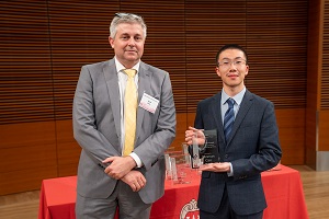 two people stand, one is holding a glass plaque