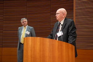 two man standing and one is by a podium