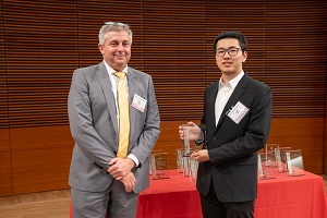 two people stand, one is holding a glass plaque
