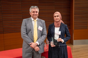 two people stand, one is holding a glass plaque